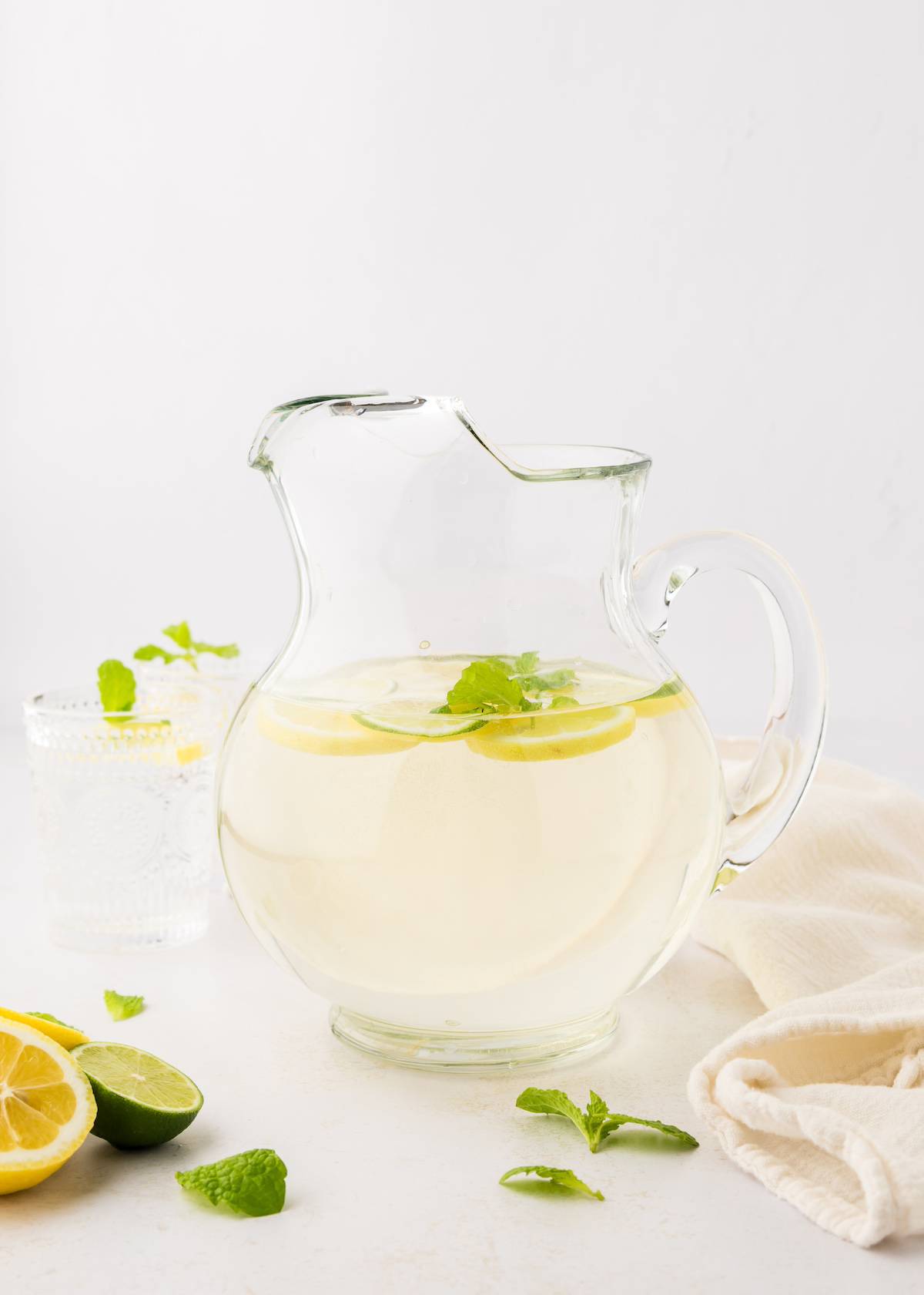 A pitcher of flavored water with mint, lemons, and lime slices.