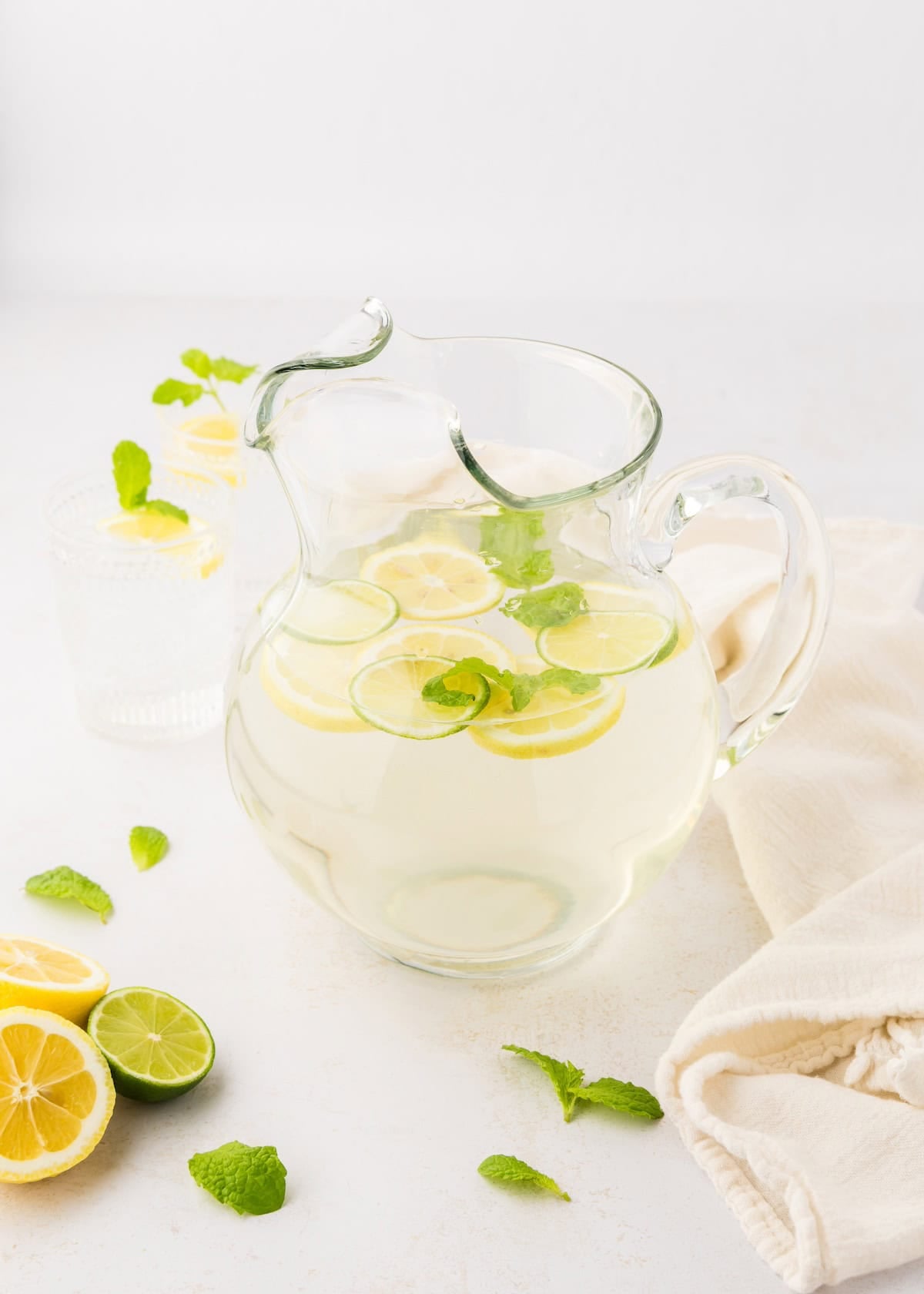 A pitcher of flavored water with mint, lemons, and lime slices.