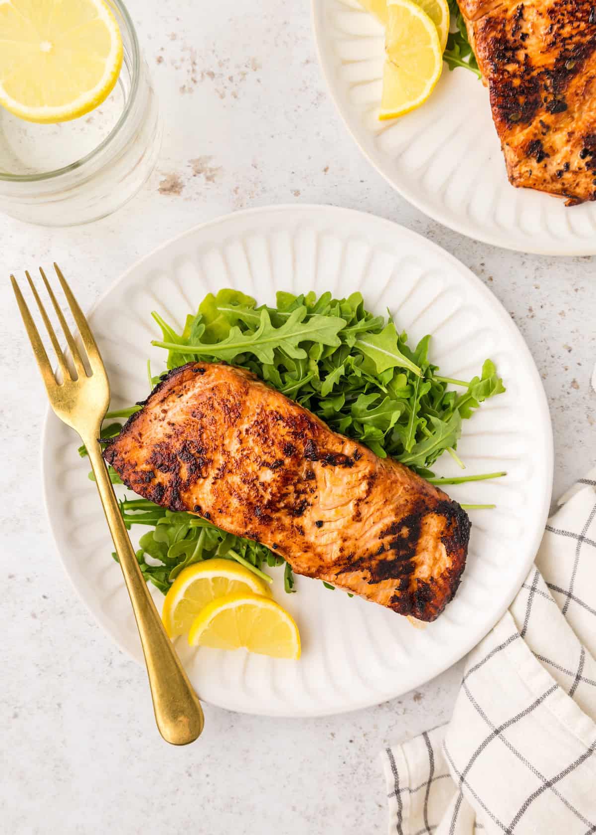 Seared Salmon served on a plate with arugula and lemon.