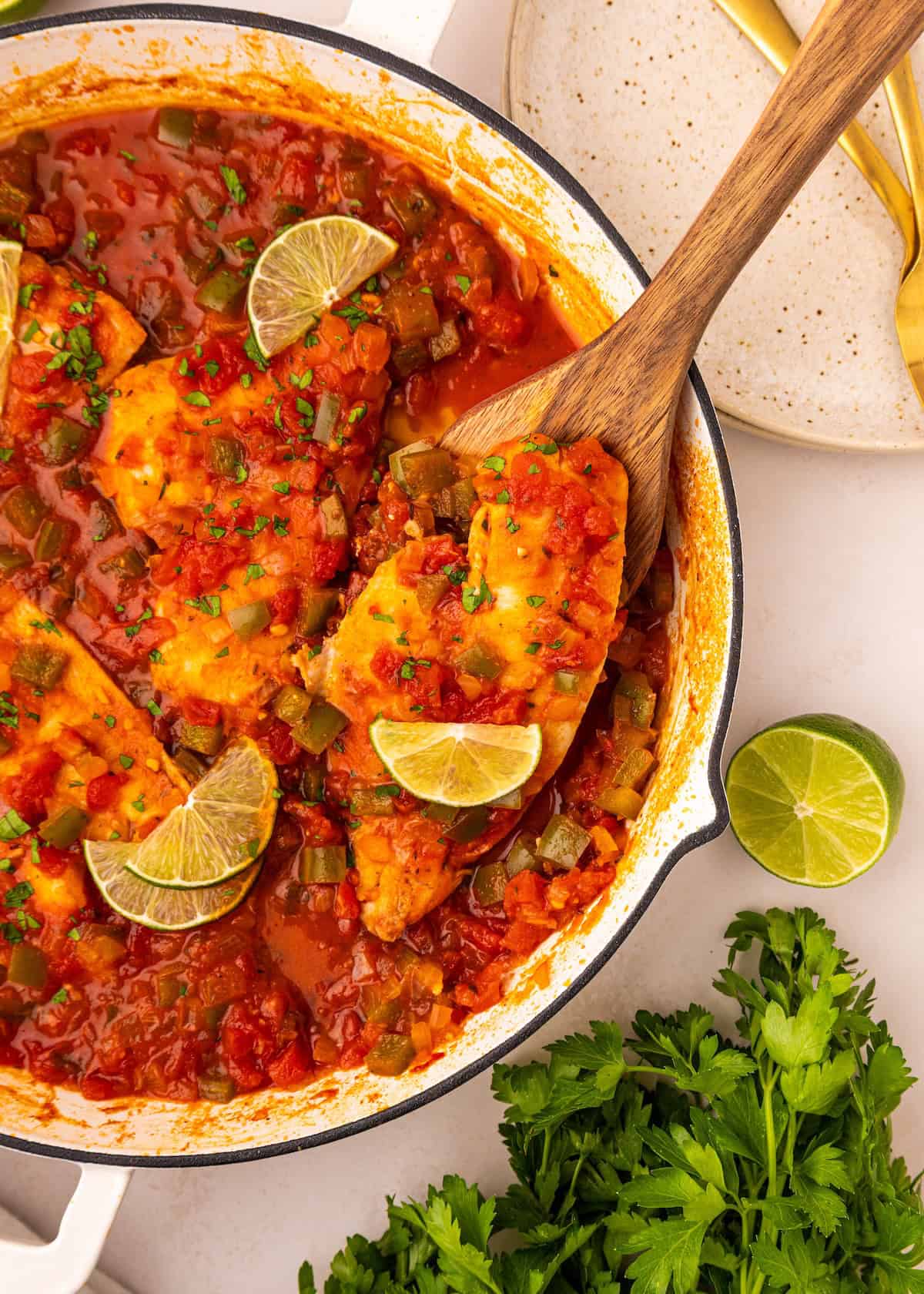 Creole fish fillets in tomato sauce with lime, garnished with parsley in a skillet.