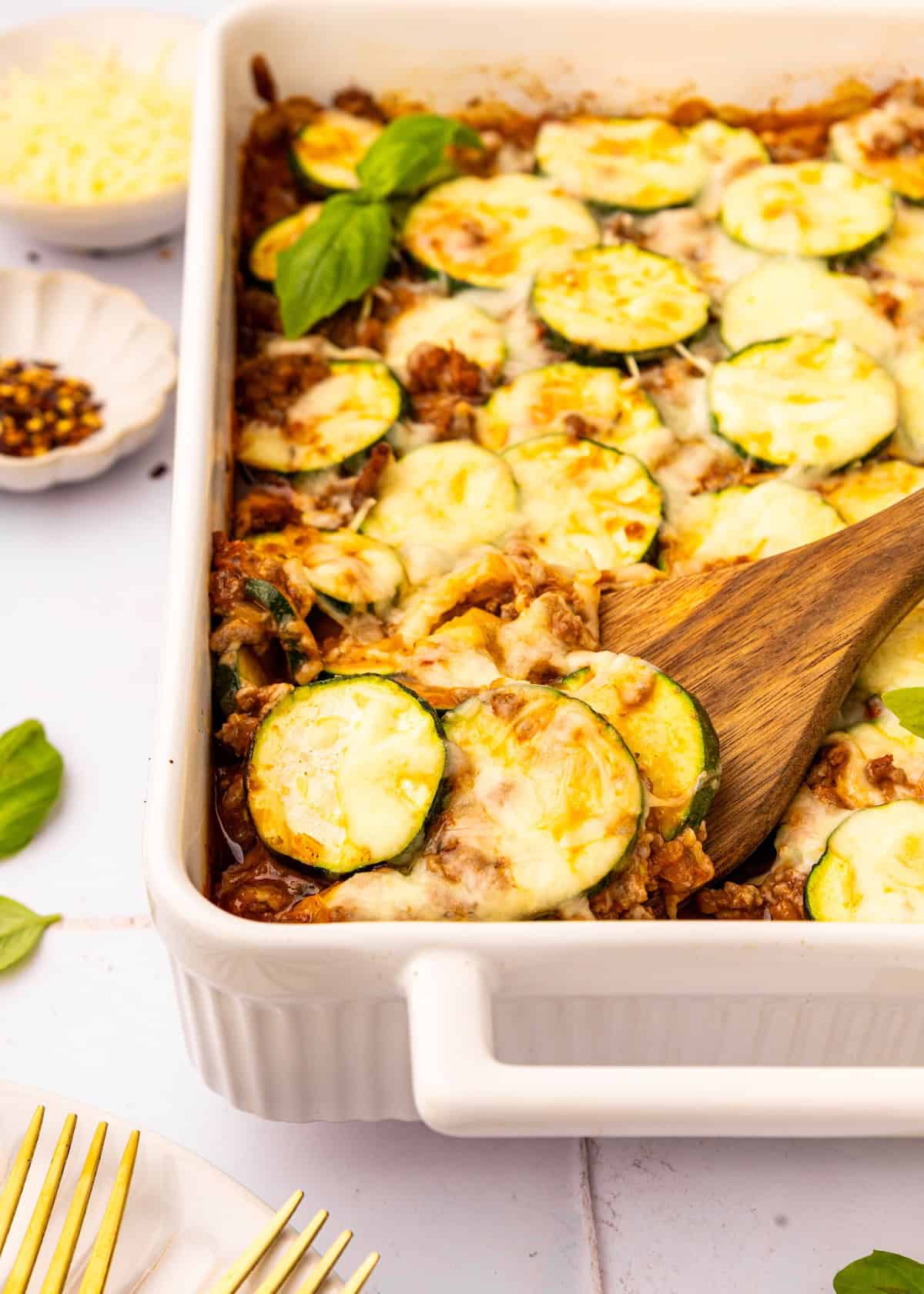 A wooden serving spatula lifting casserole out of dish.