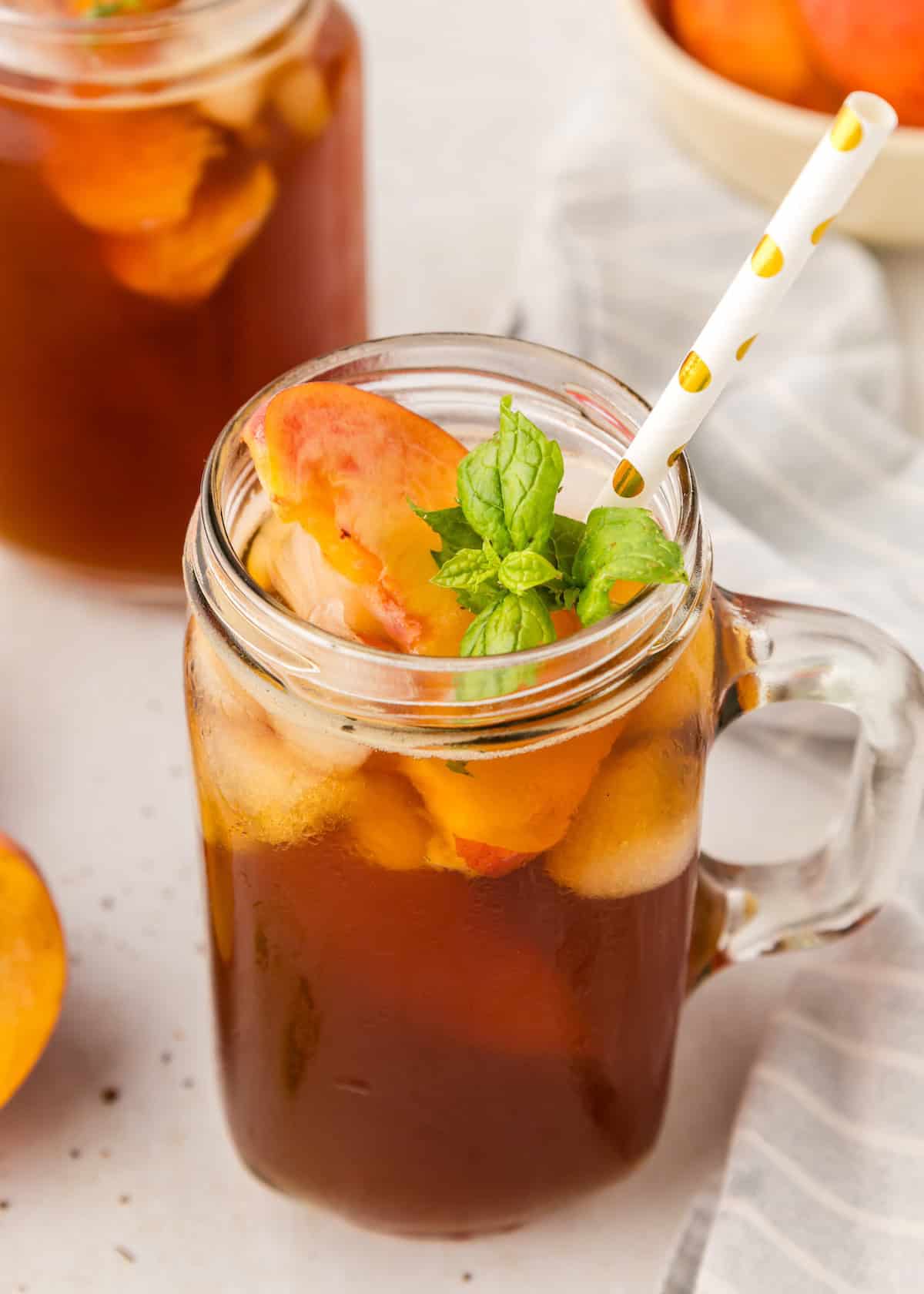 peach iced tea with sprig of mint and straw