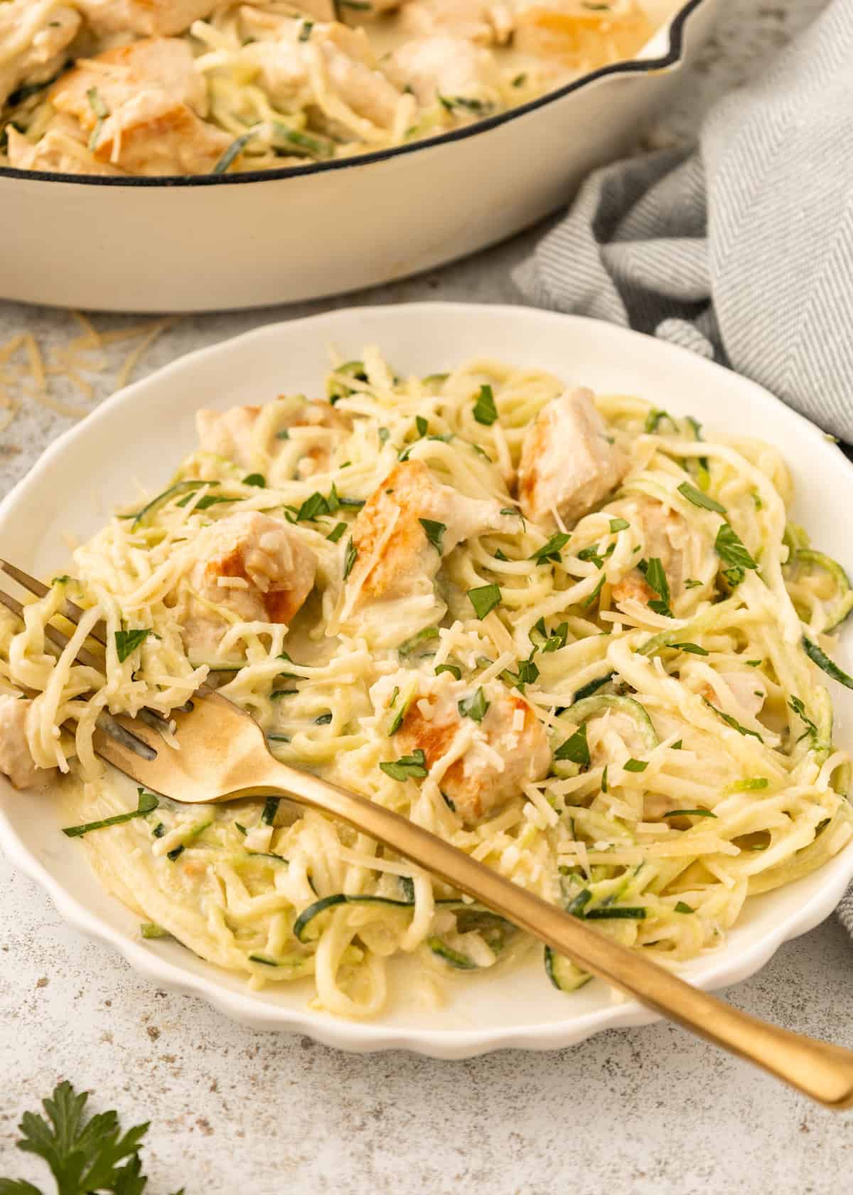 Creamy Chicken Zucchini Noodles topped with parsley, served on a white plate.