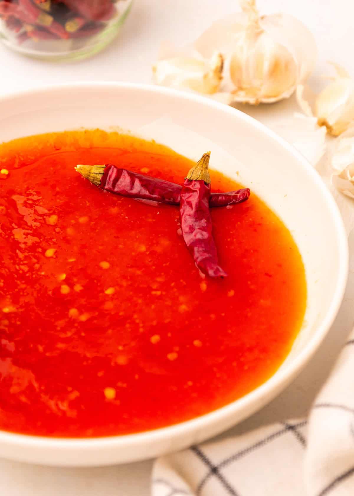 A bowl of Red Chili Sauce topped with two dried red chili peppers.