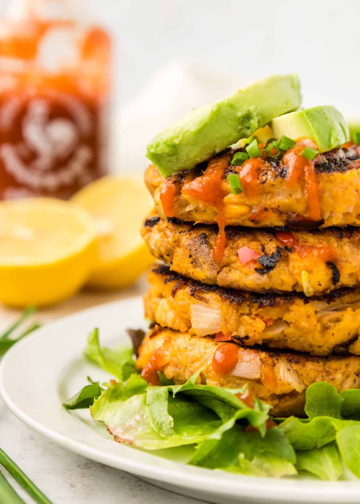 Tuna Cakes stacked and plated with avocado and sriracha on top.
