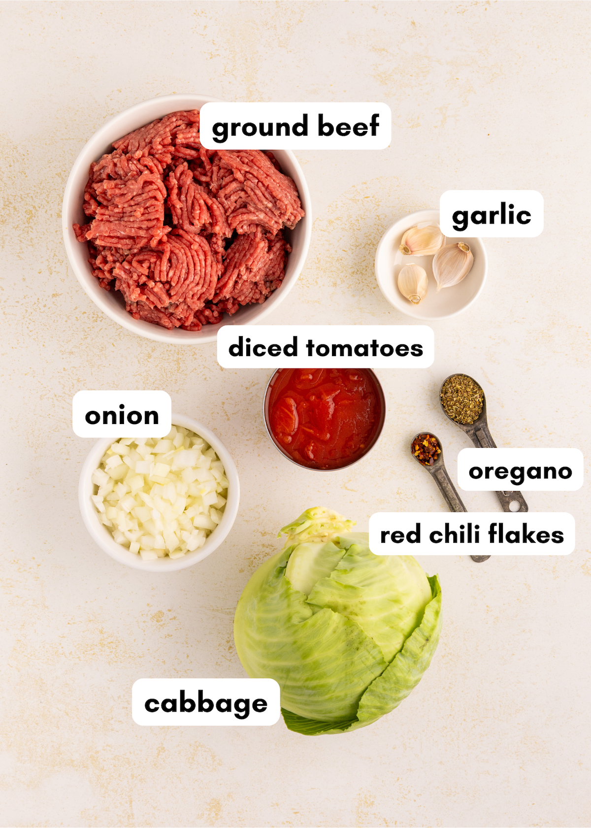 Labeled ingredients for Amish ground beef and cabbage: garlic, onion, tomatoes, oregano, chili flakes.
