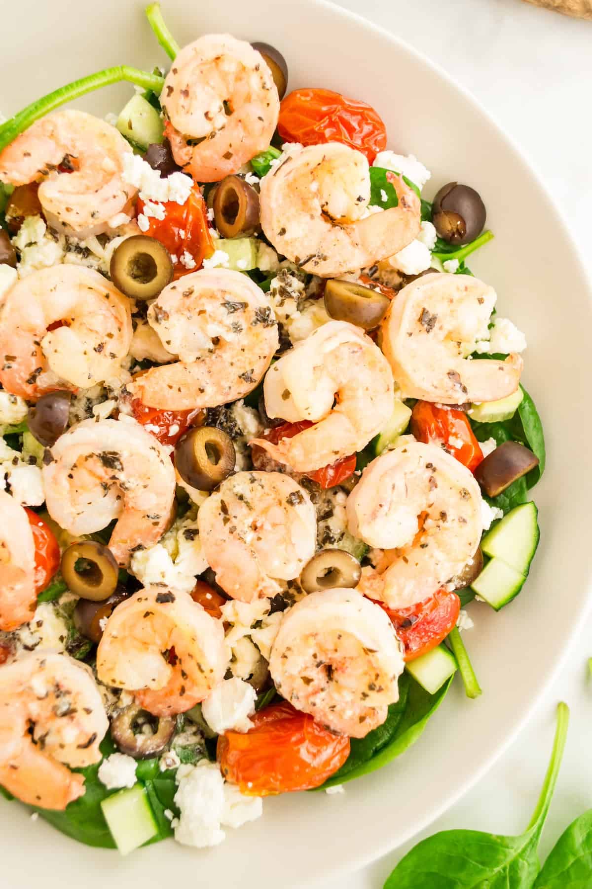 Greek shrimp salad served in bowl, topped with shrimp.