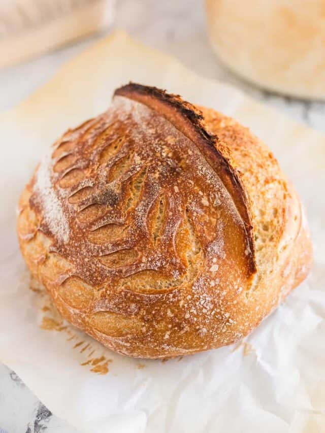 A loaf of sourdough bread with decorative scoring patterns on the top.