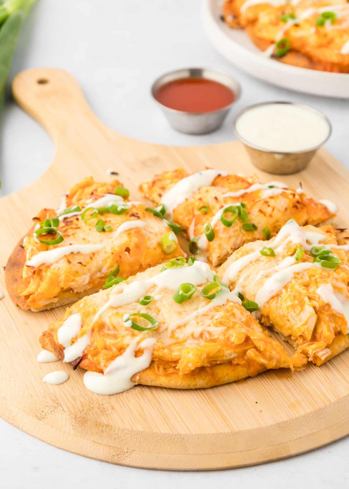 Flatbread drizzled with blue cheese and green onions on a wooden board.