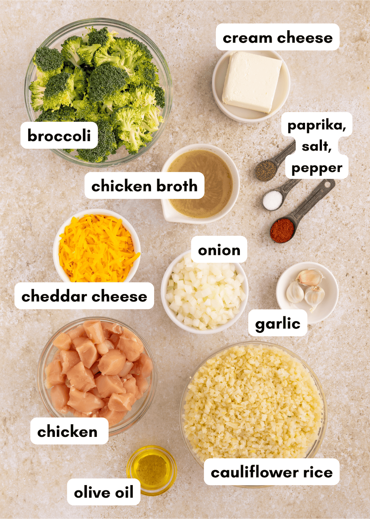 Ingredients for a chicken broccoli and rice casserole labeled on a beige countertop.