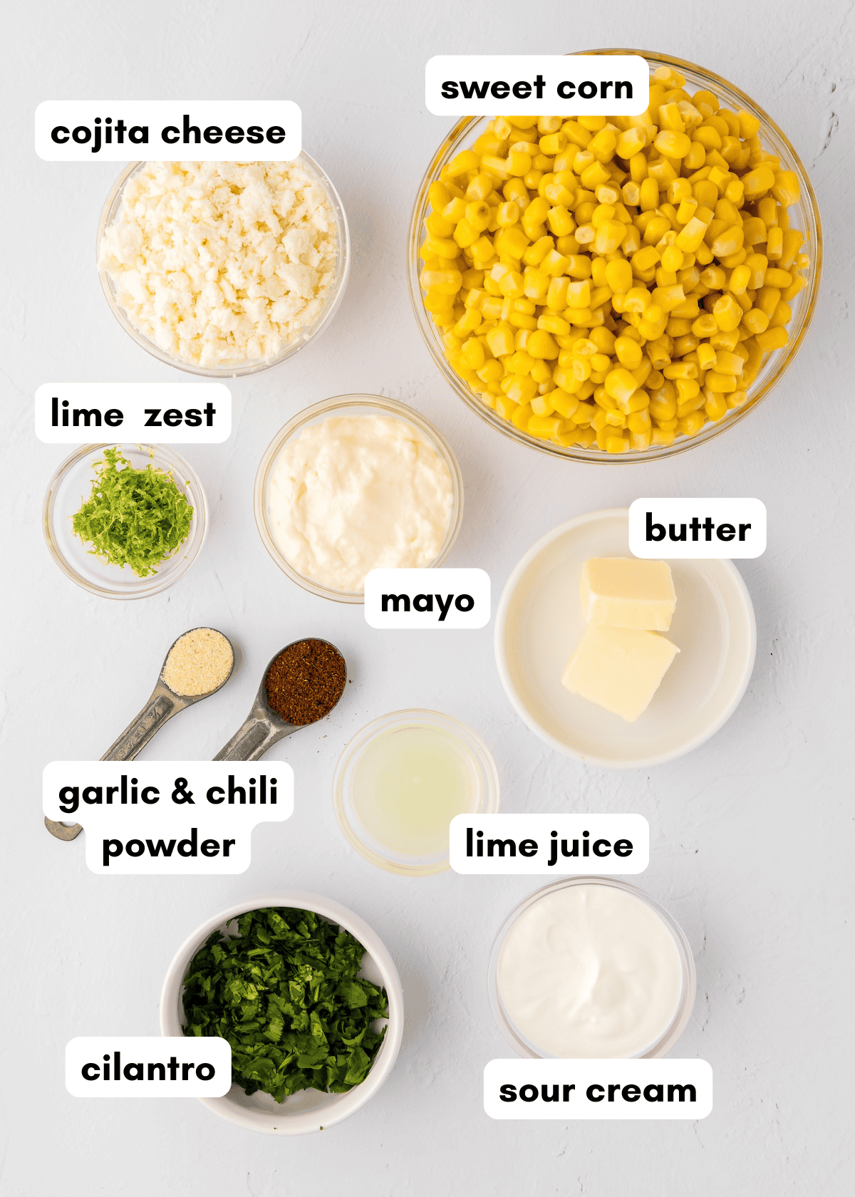 Bowls of Mexican Street Corn Dip with cotija cheese, lime, cilantro, mayo, and sour cream.