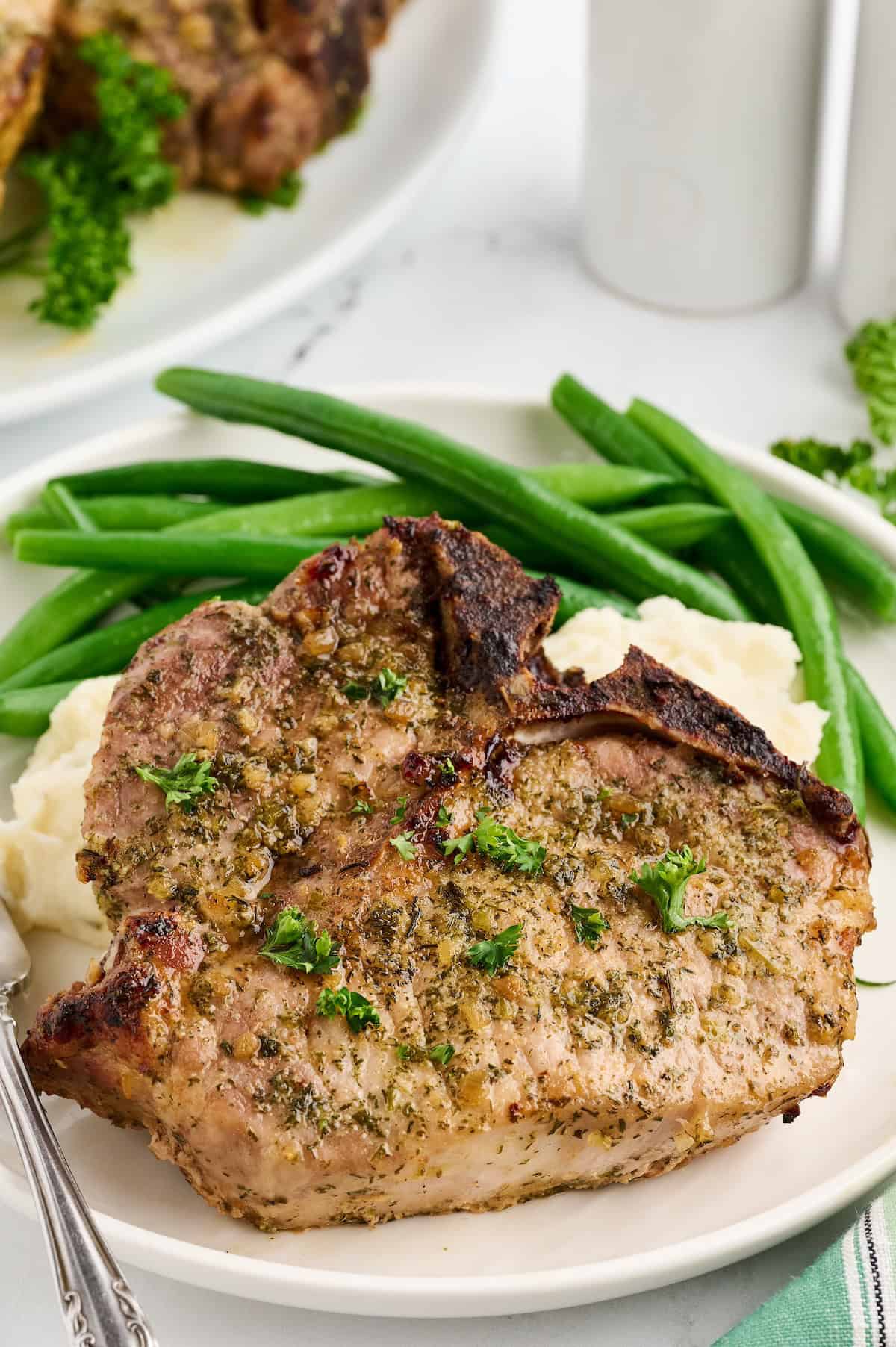 Baked Ranch Pork Chops served with mashed potatoes and green beans on a white plate.