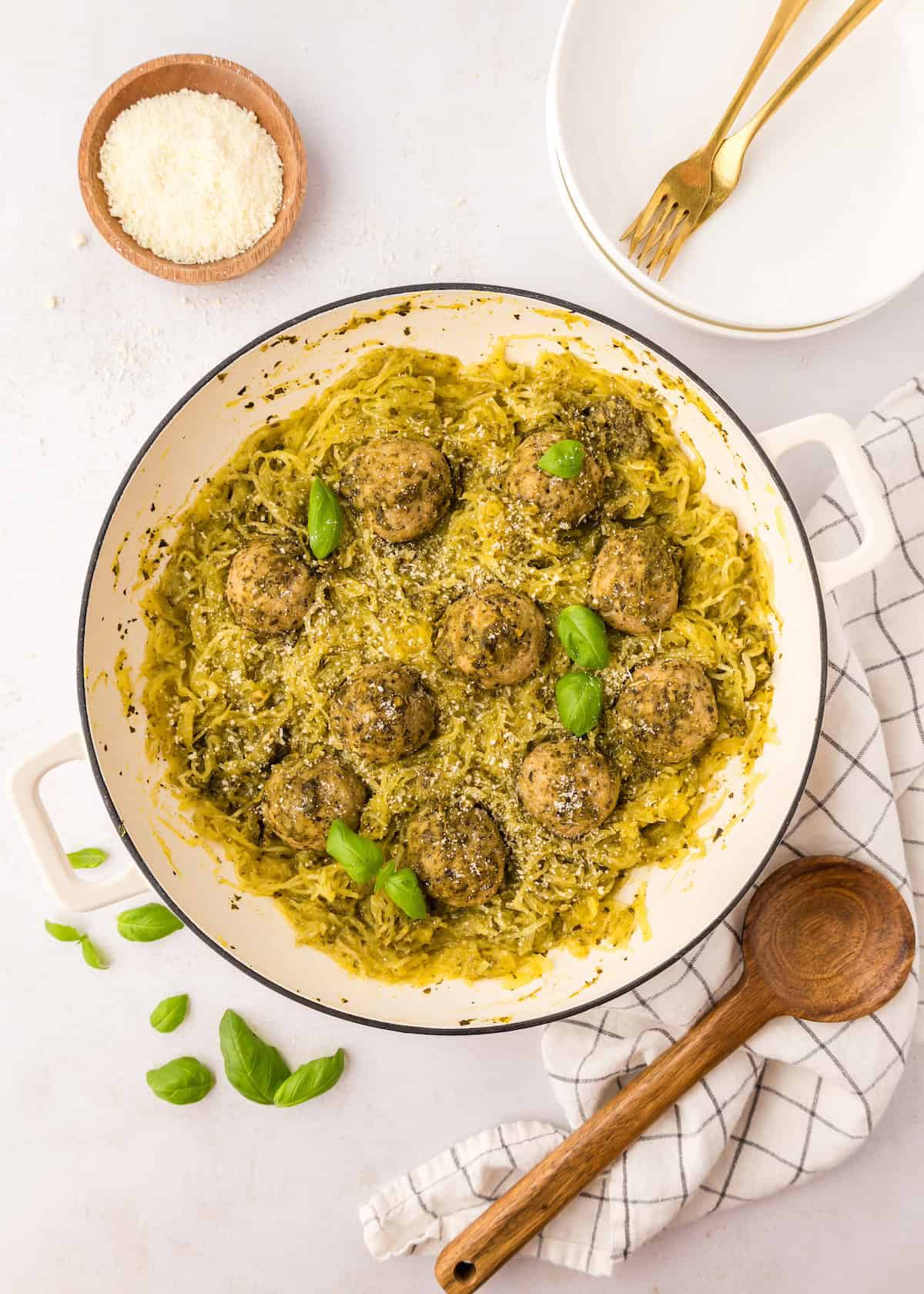 A pan of Pesto Chicken Meatballs with fresh basil leaves.