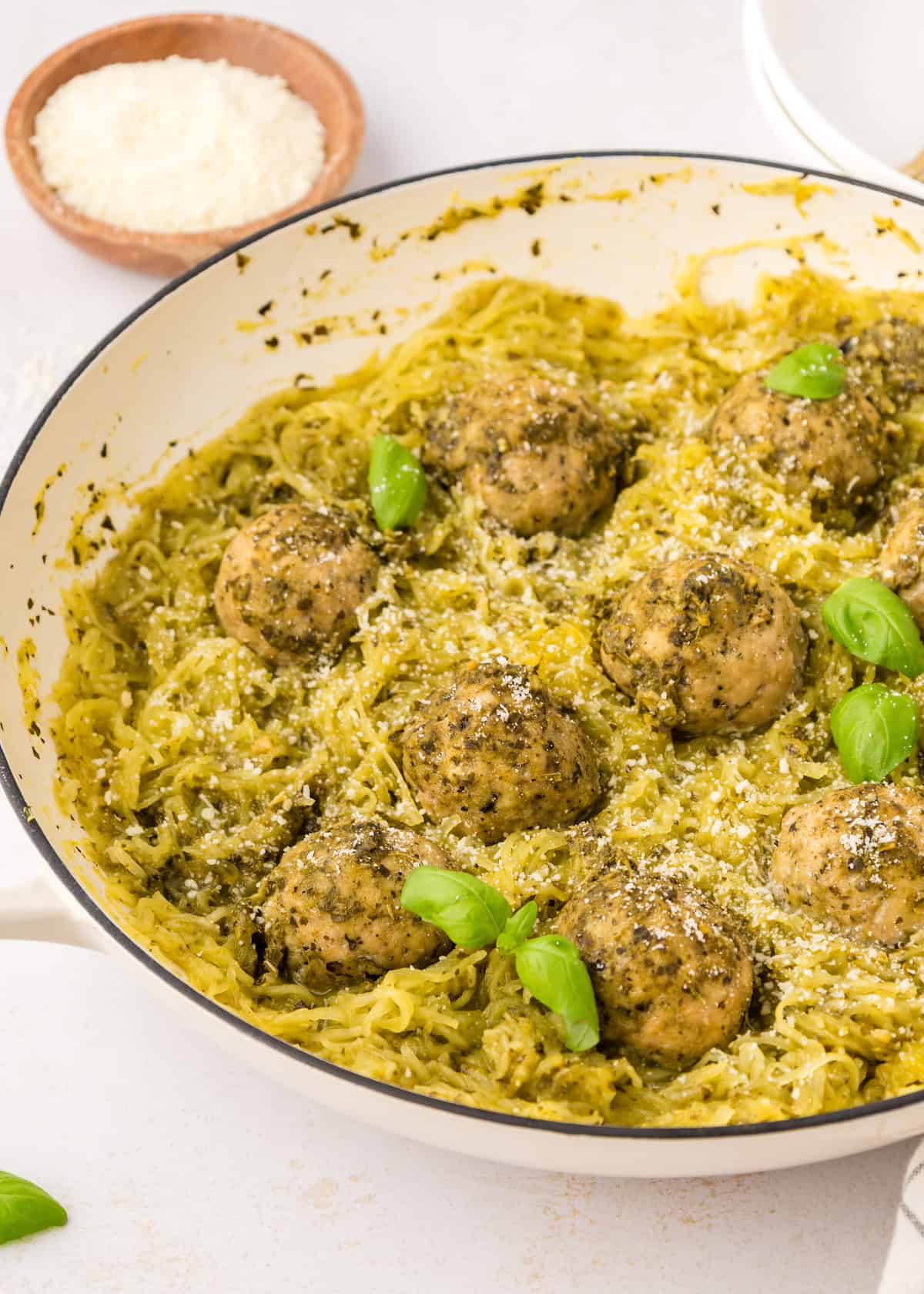 Pesto chicken meatballs with spaghetti squash, garnished with basil and parmesan.