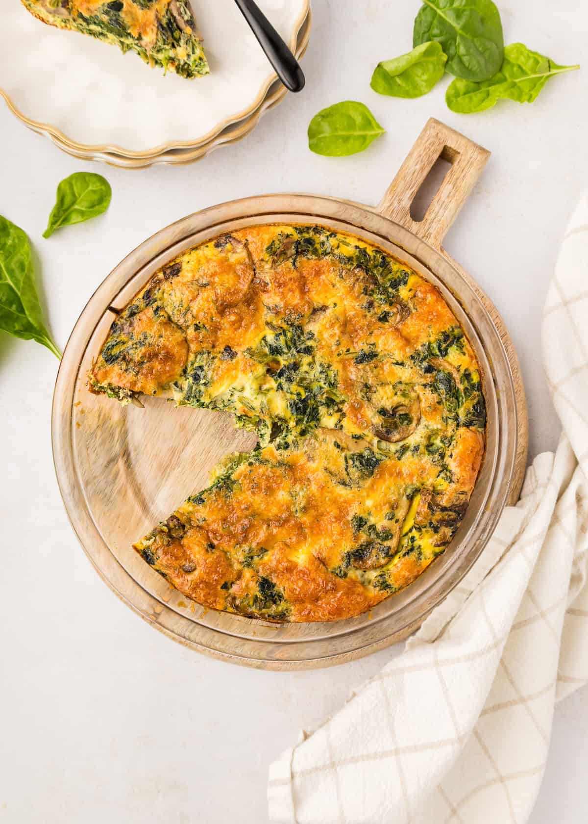 Crustless spinach quiche with slice on plate.