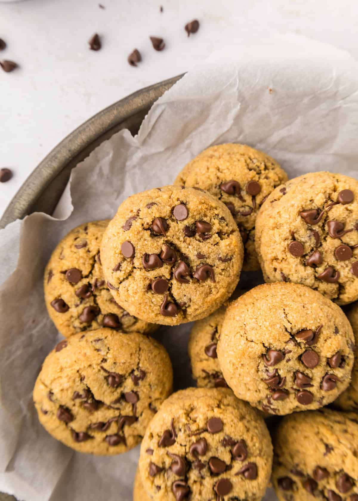 A plate of healthy chocolate chip cookies on parchment paper, viewed from above.