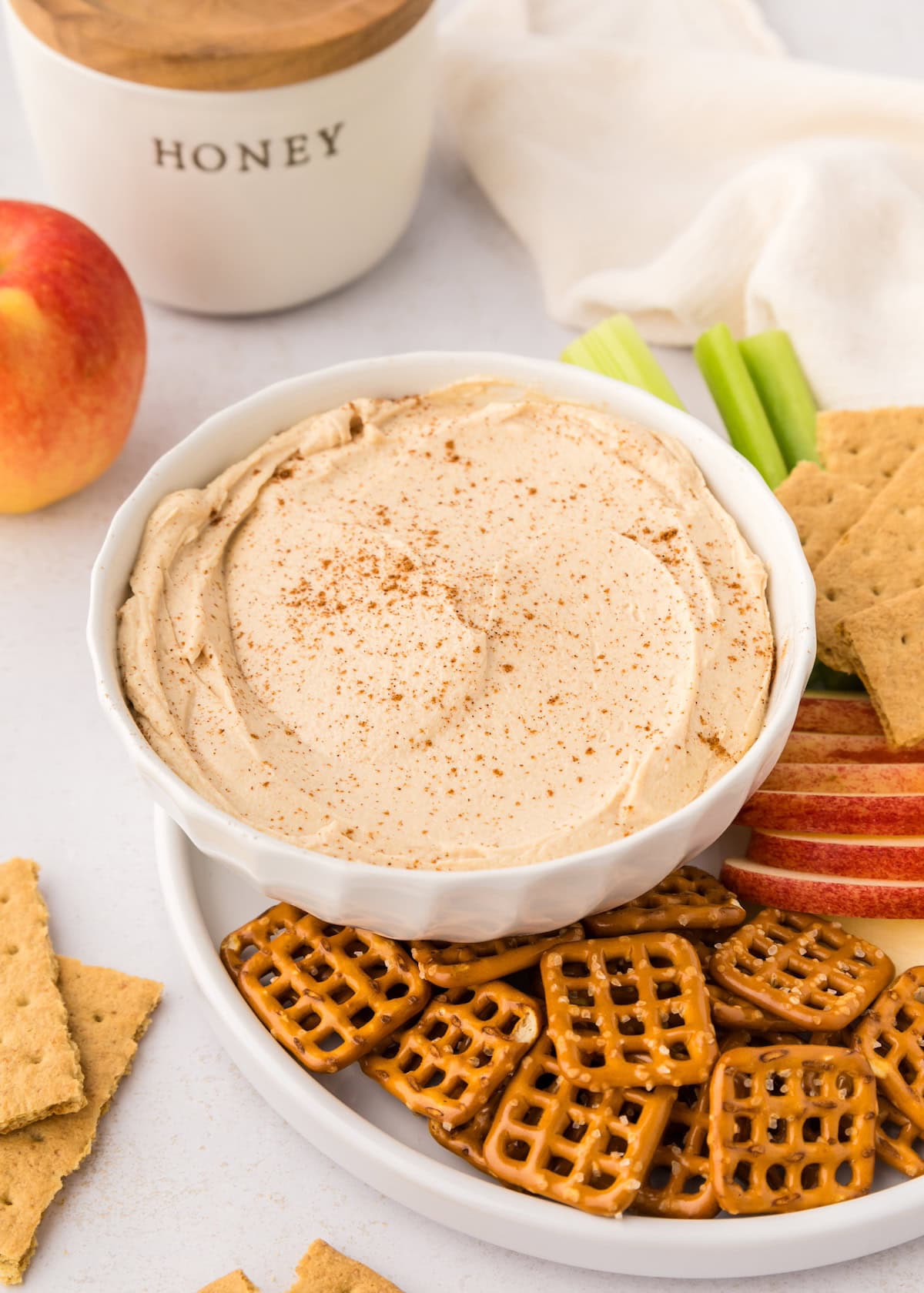 A bowl of Peanut Butter Yogurt Dip with pretzels, apple slices, celery, and graham crackers.