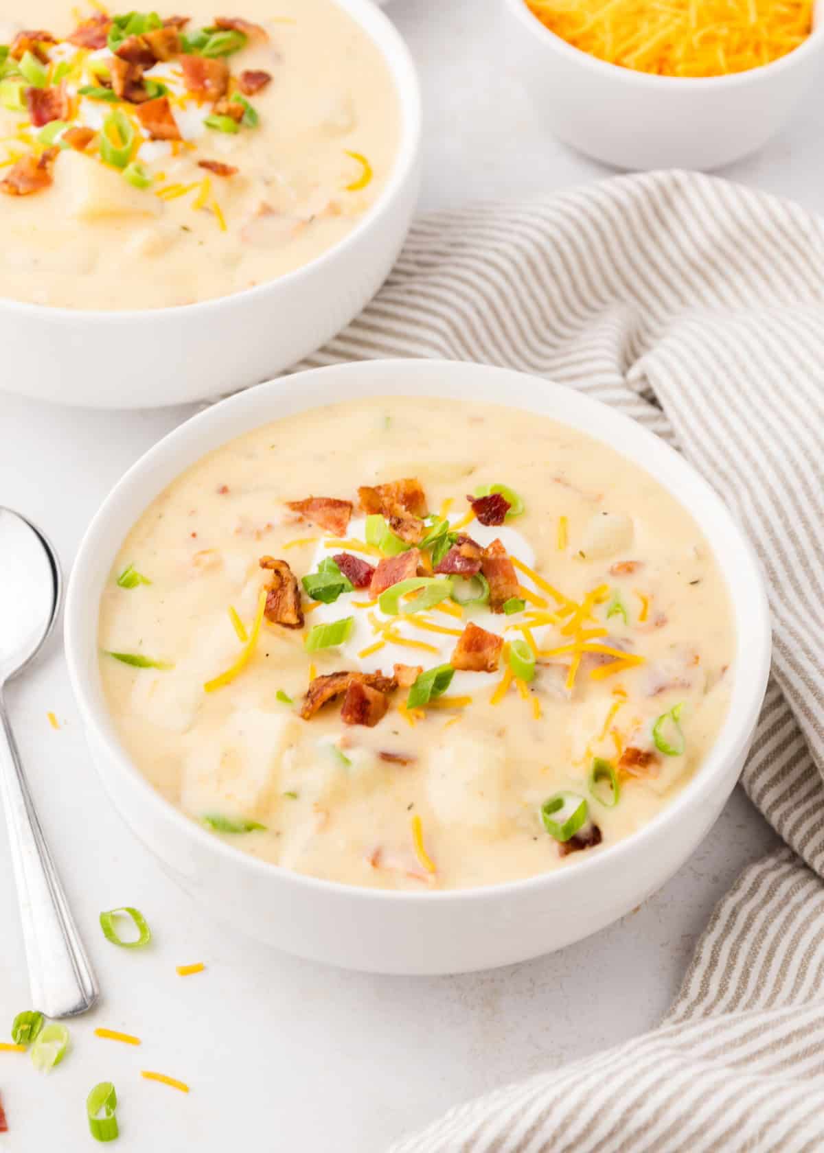 Crockpot Potato Soup served in a bowl with bacon, cheese, sour cream, and more.