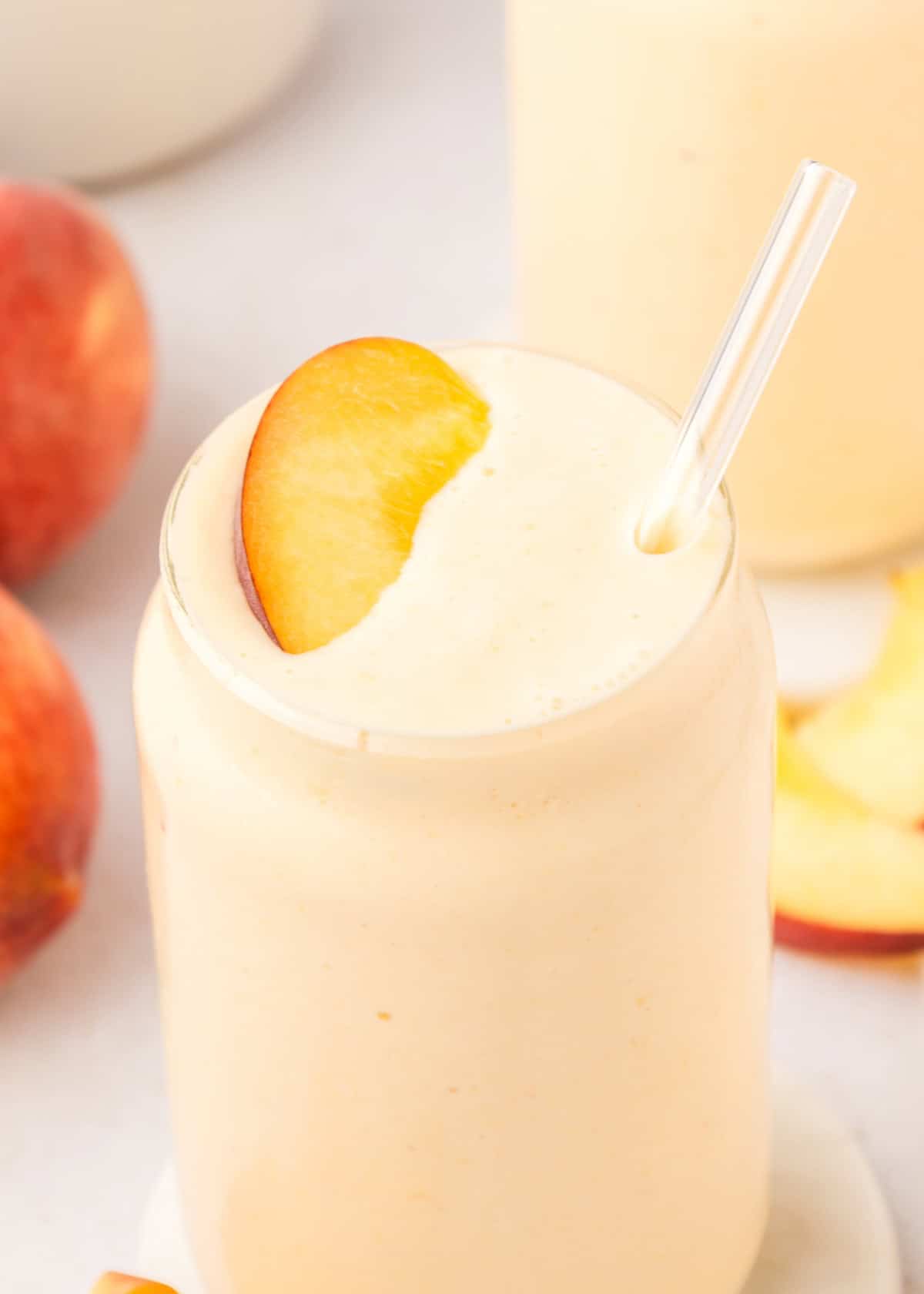 peach smoothie garnished with a peach slice
