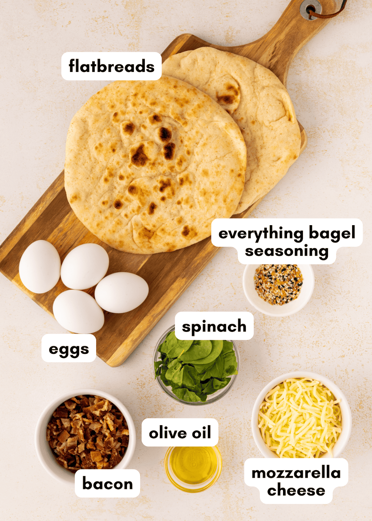 Breakfast Flatbread with eggs, bacon, spinach, mozzarella, and seasoning on a board.