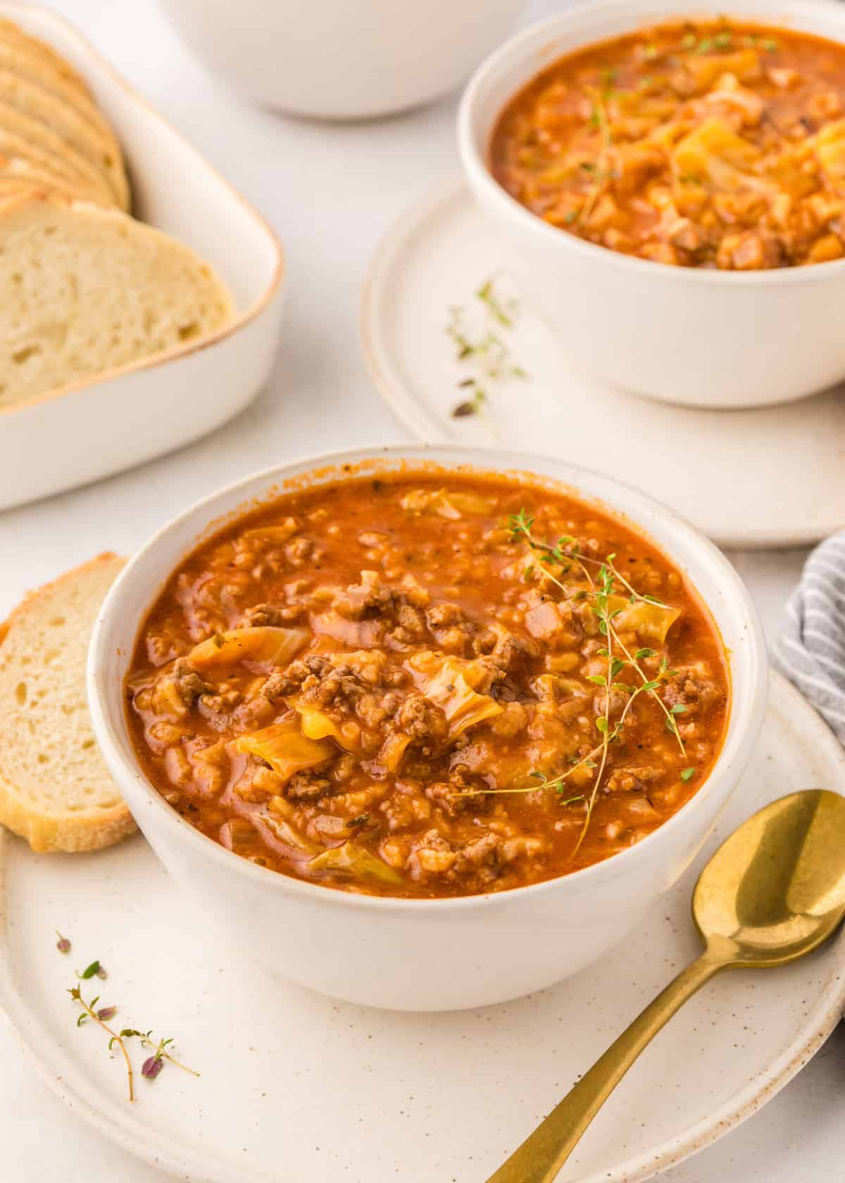 Cabbage roll soup served in bowl with bread.