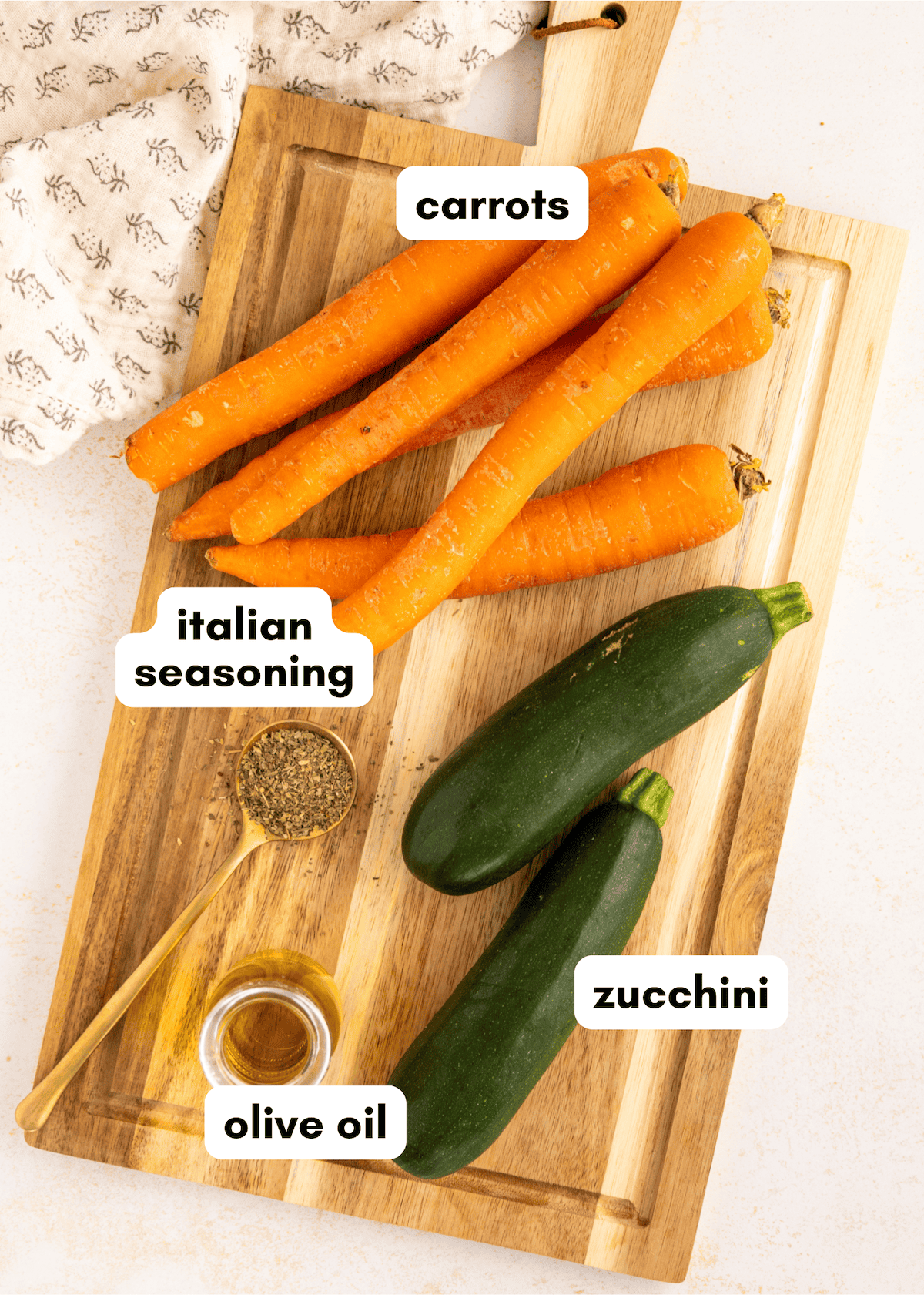 Roasted Carrots and Zucchini with olive oil and Italian seasoning on a wooden cutting board.