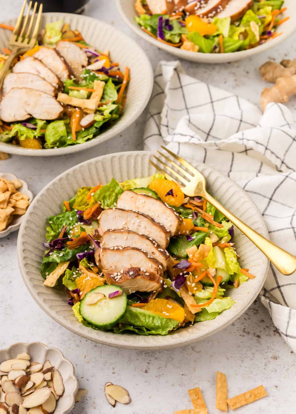 Asian Chicken Salad with sliced chicken, mandarin oranges, cucumbers, and greens in a bowl.