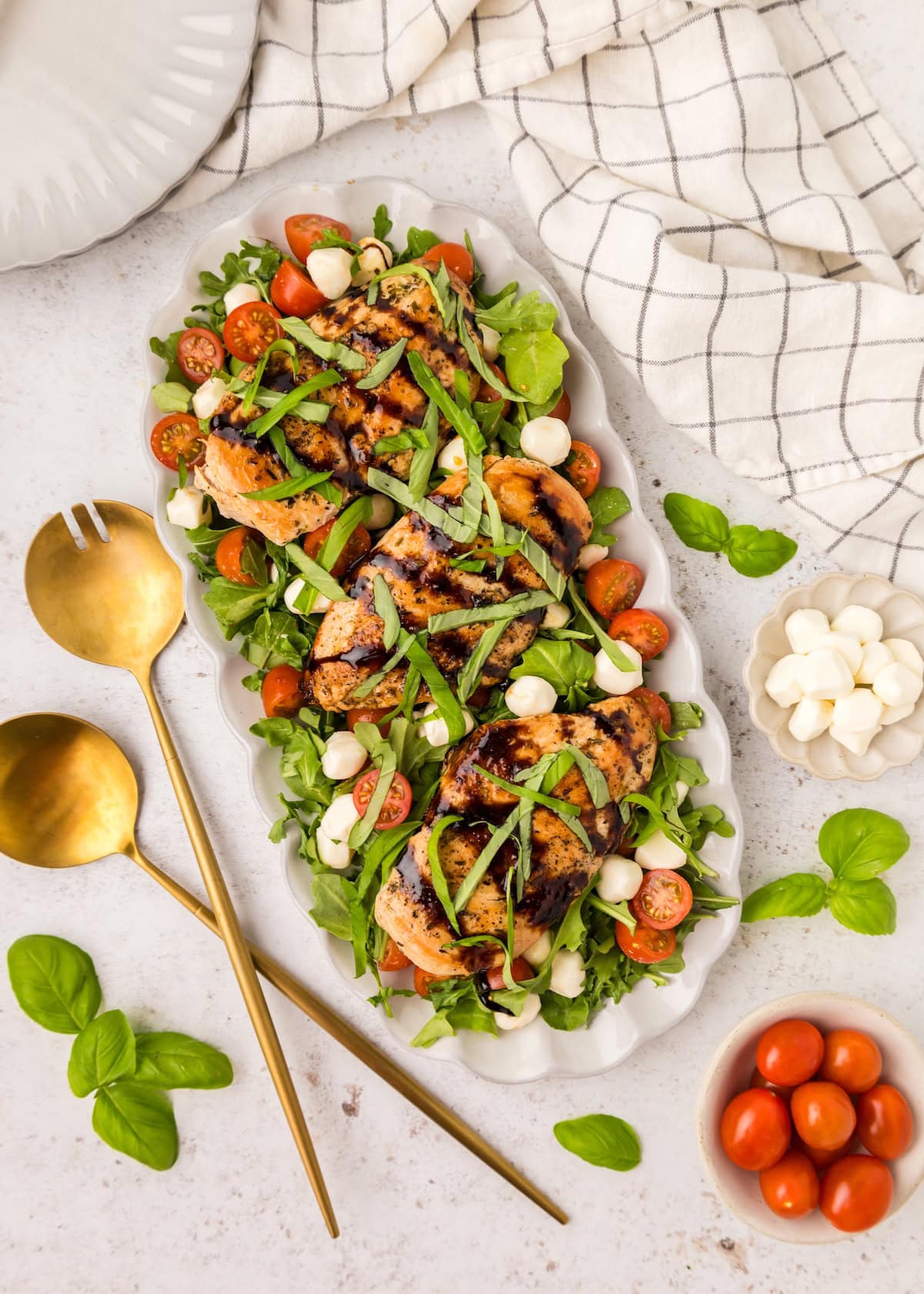 Top shot of Chicken Caprese Salad with serving utensils.