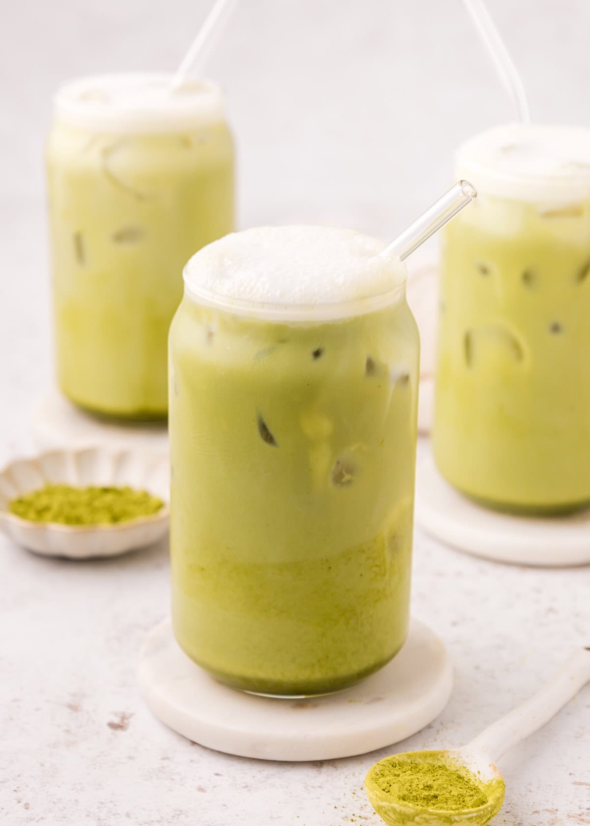 Iced Matcha Lattes in jars with glass straws and froth