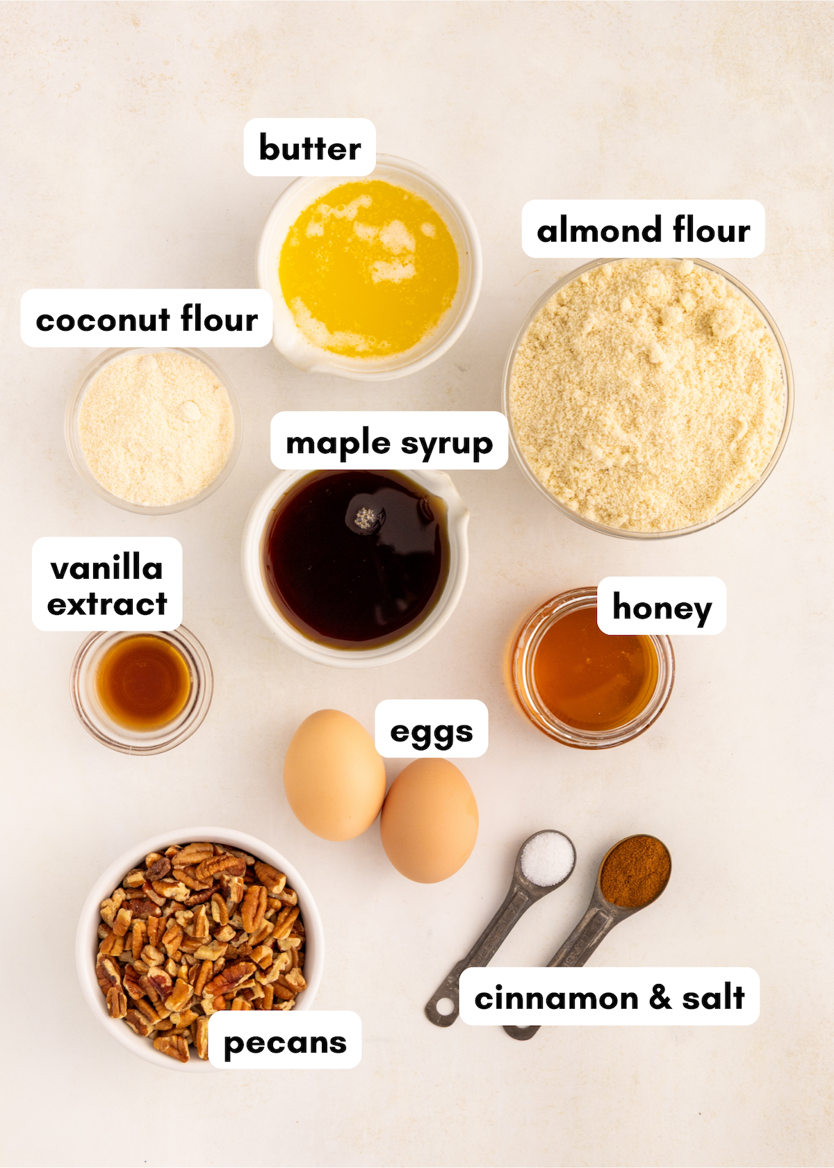 Bowls of labeled ingredients for baking maple pecan pie bars: almond flour, eggs, honey, and more.