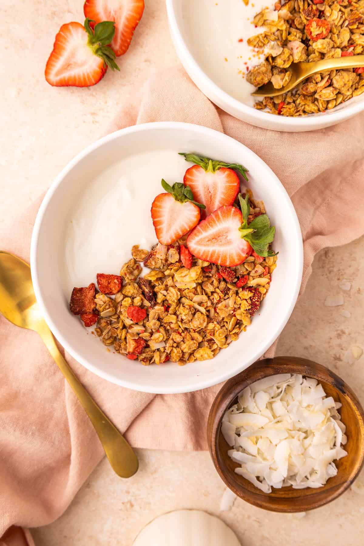 Strawberry Granola in a white bowl with yogurt and fresh strawberries.