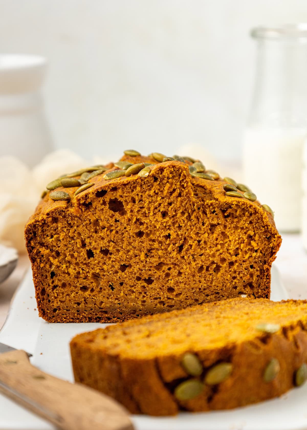 Pumpkin Bread loaf topped with pepitas, with a slice cut in front.