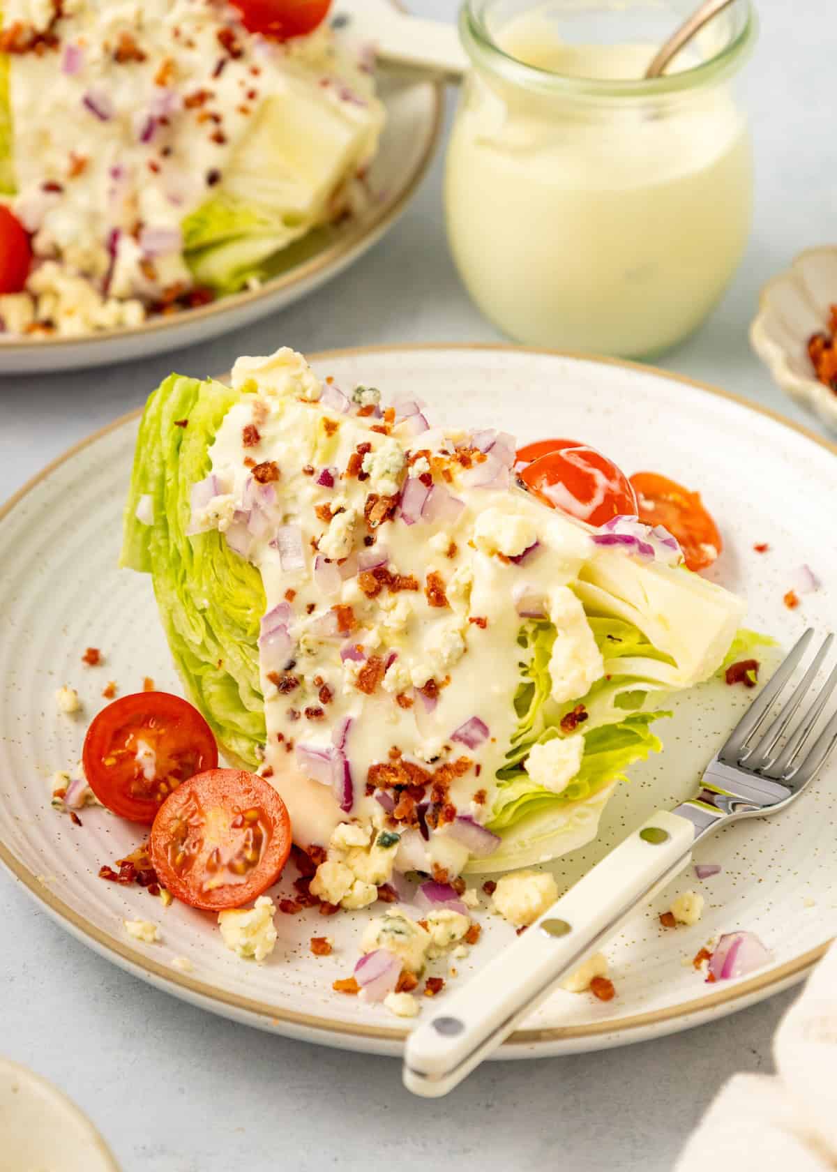 Classic Wedge Salad with crispy bacon, tomatoes, onions, cheese, and creamy dressing.