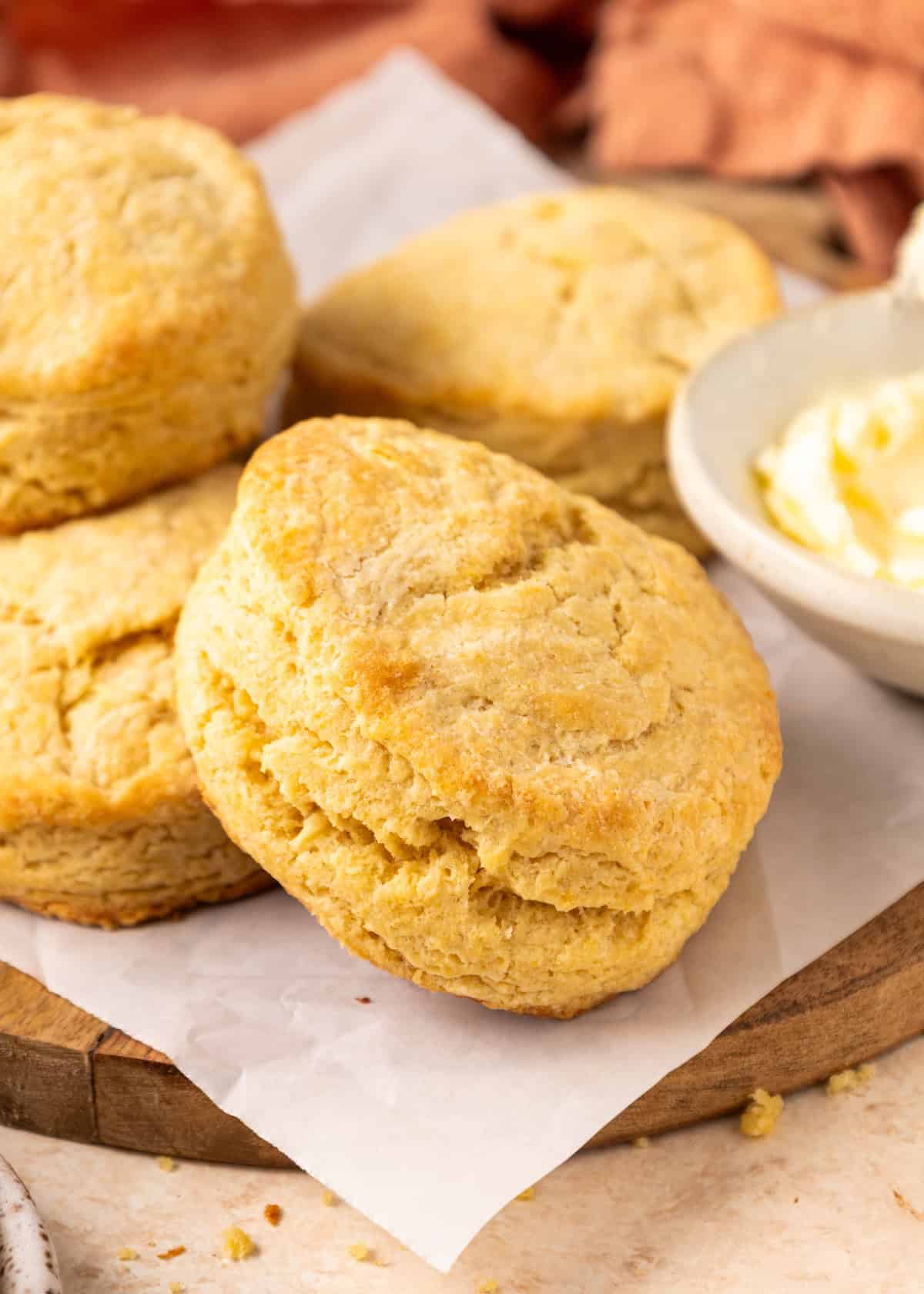 Golden brown Einkorn Biscuits on parchment paper next to a bowl of creamy butter.