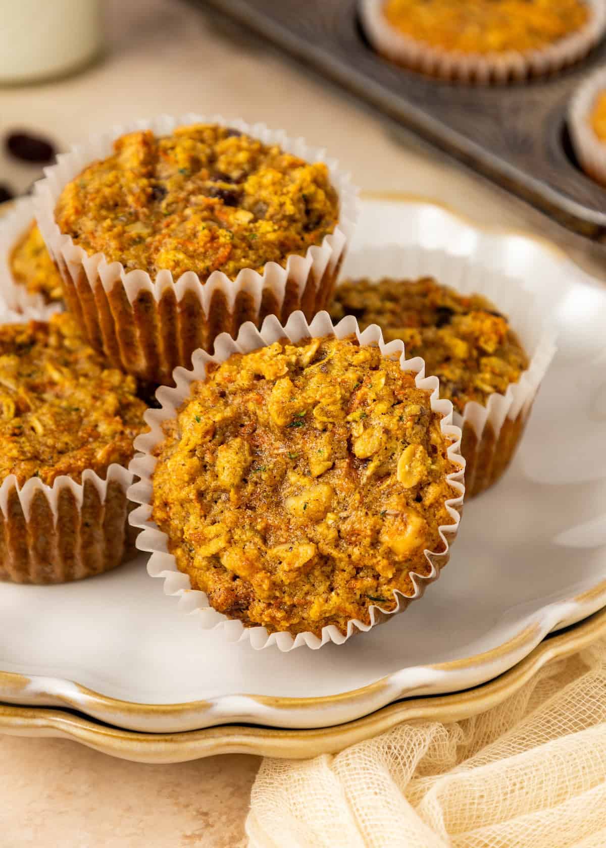 Three Superhero Muffins in paper liners stacked on a white plate, muffin tray in the background.