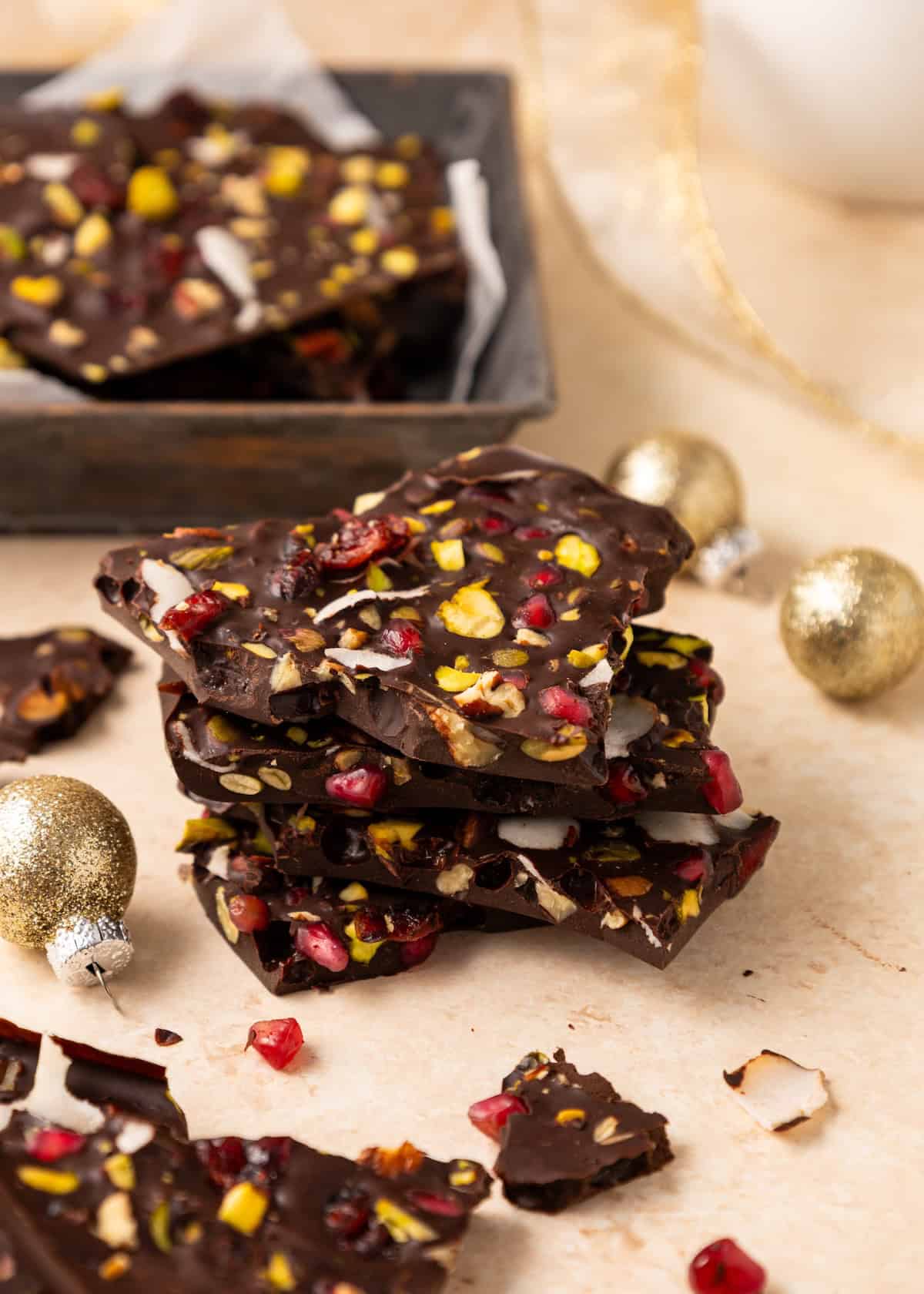 Dark Chocolate Bark stacked with nuts and fruit, surrounded by shimmering gold ornaments.