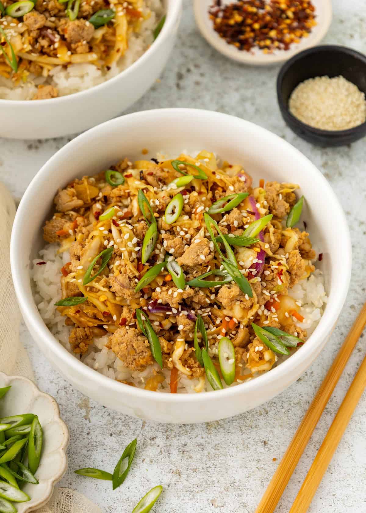 A bowl of rice topped with ground meat, veggies, sesame seeds—like Egg Roll Bowls.