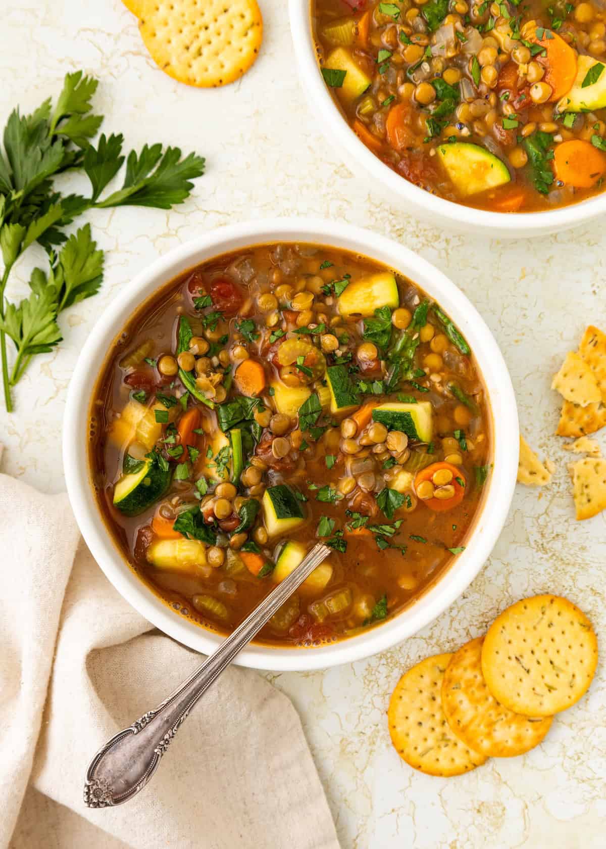 Bowl of hearty Lentil Vegetable Soup with crackers and fresh parsley on the side.