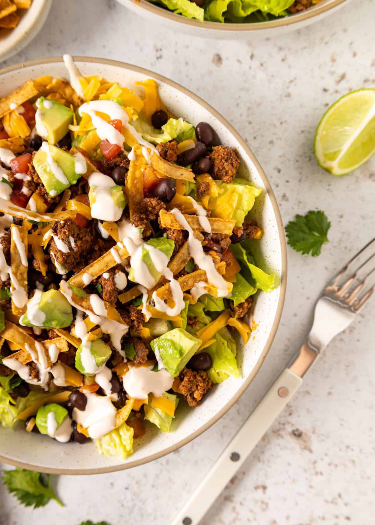 A flavorful Taco Salad with lettuce, beans, avocado, cheese, meat, and creamy dressing.