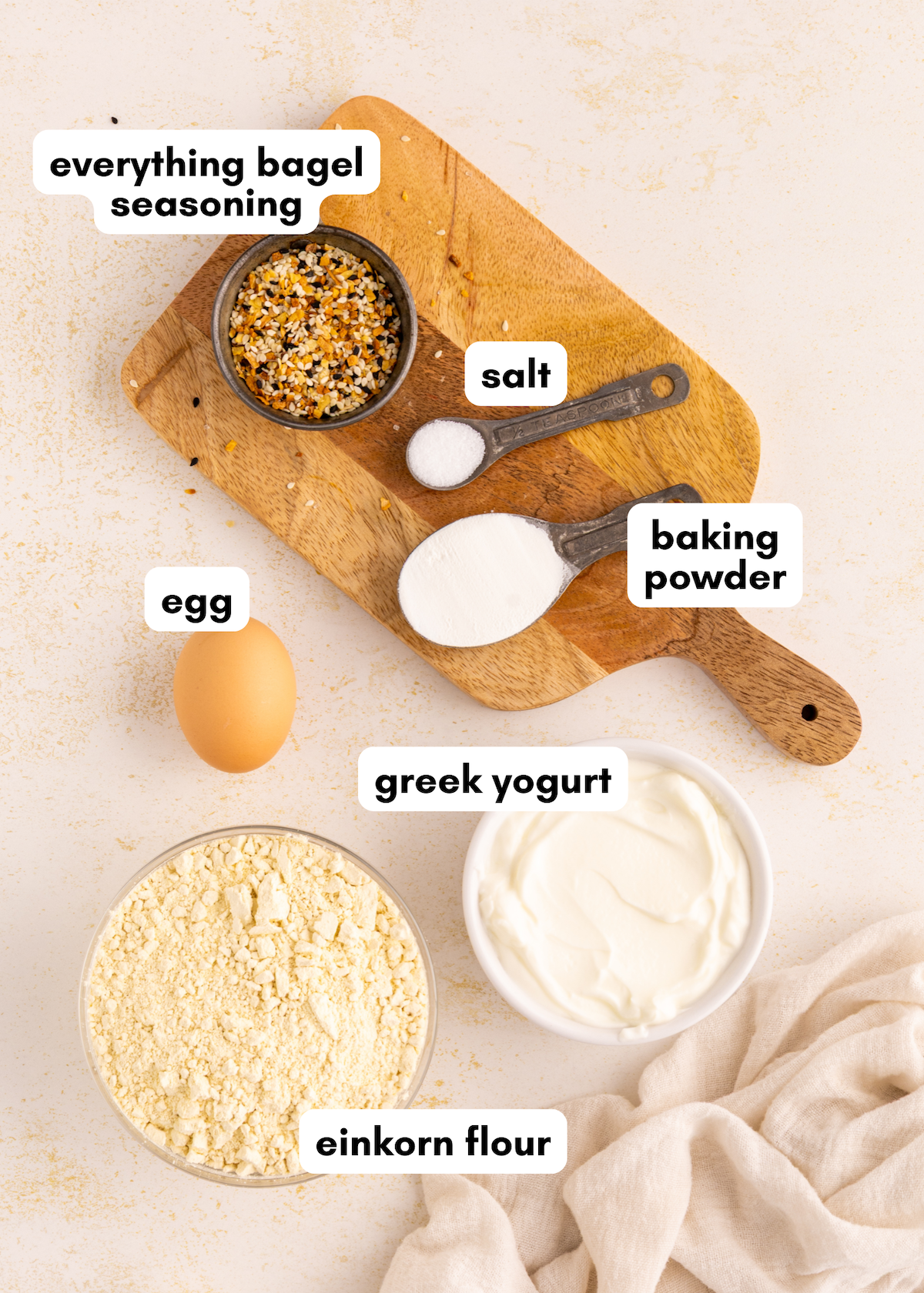 Labeled ingredients for Greek Yogurt Bagels on a wooden board and countertop.