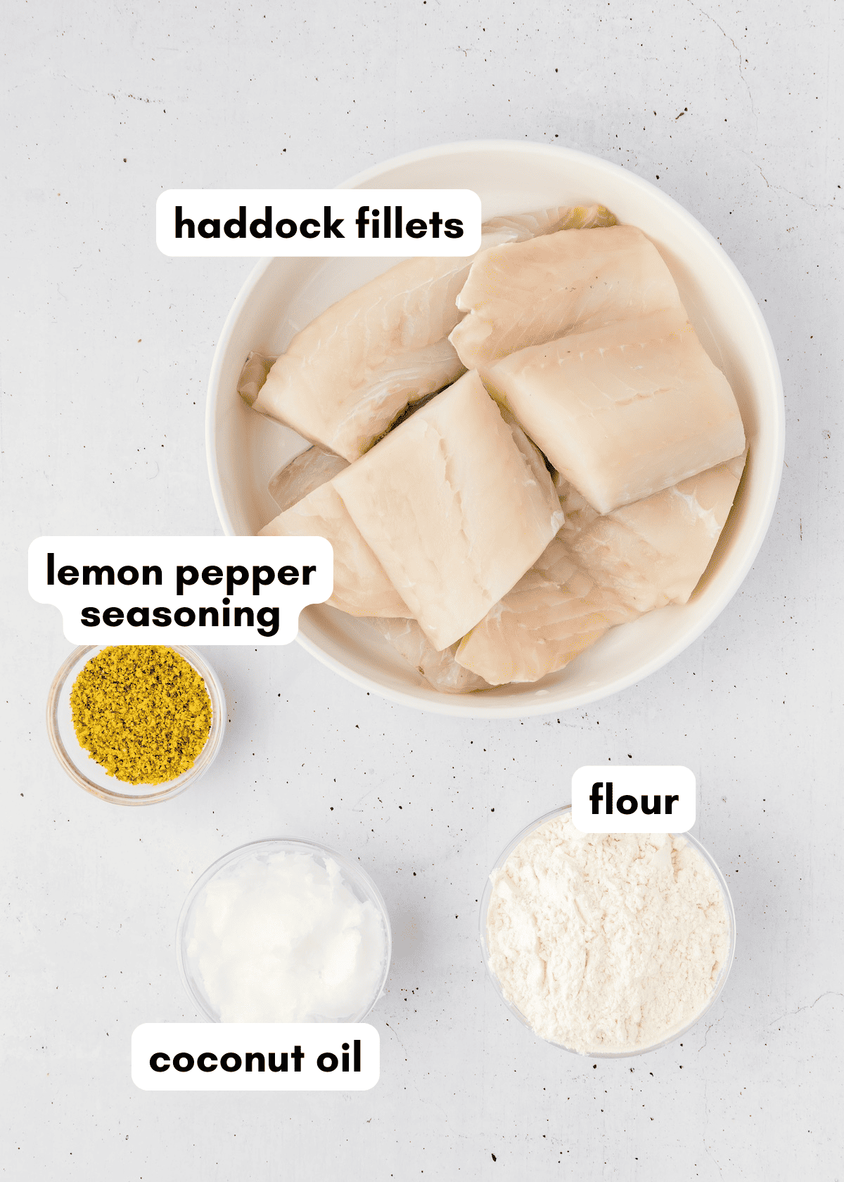 A bowl of Lemon Pepper Fish fillets, flour, and coconut oil on a white surface.