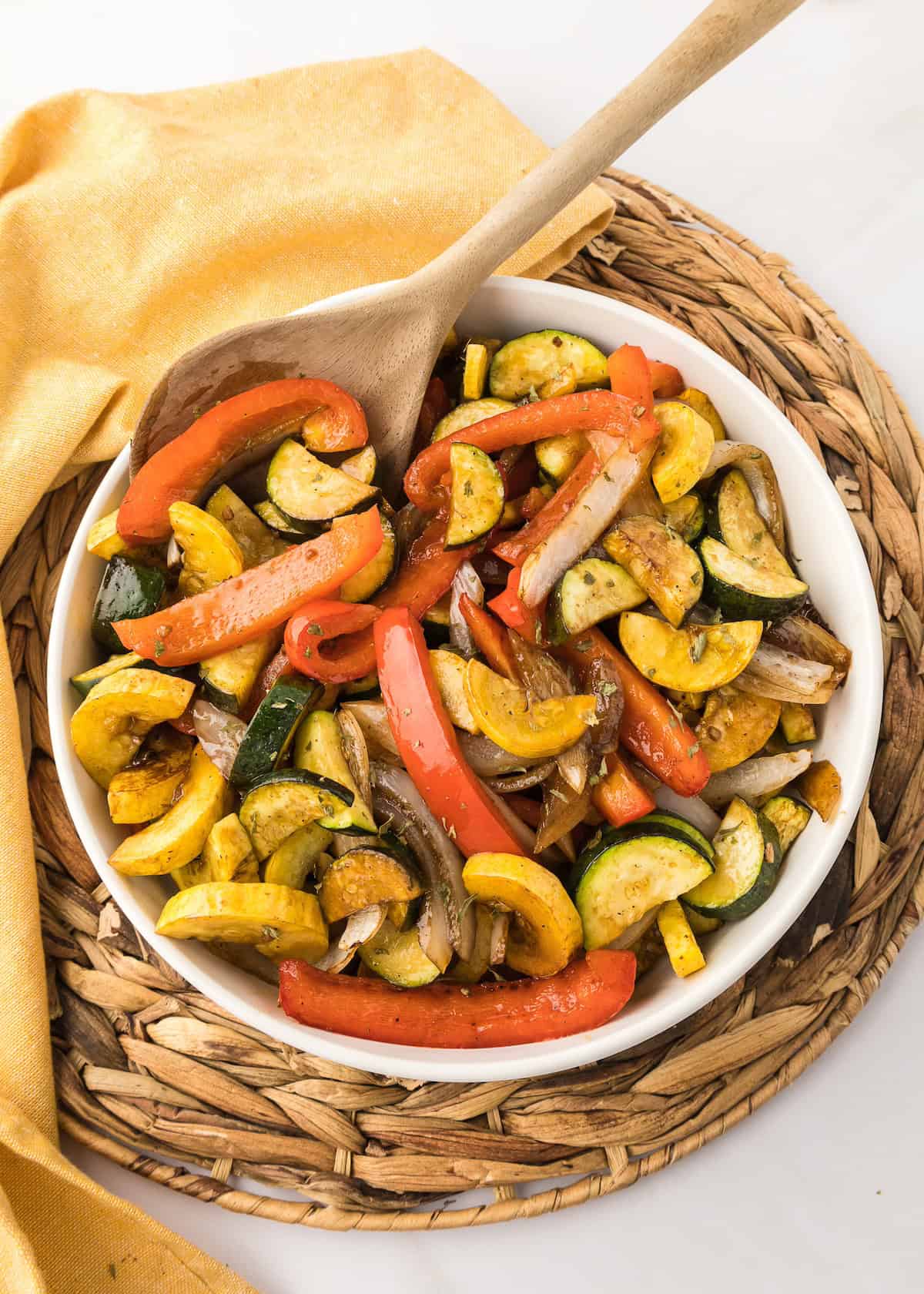 A bowl of roasted vegetables, including zucchini, squash, bell pepper, and onions.
